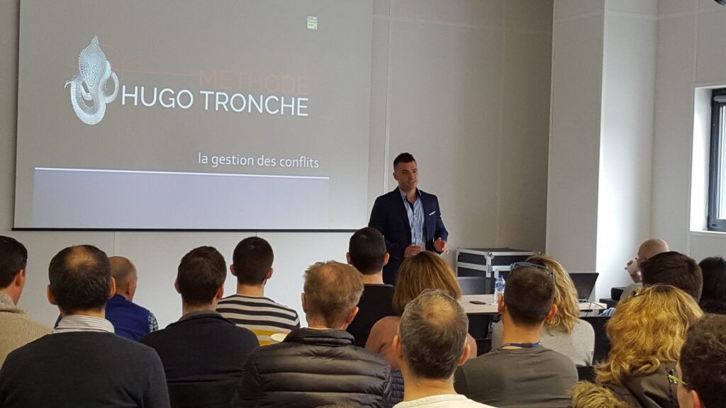 Hugo Tronche anime une conférence sur la gestion des conflits devant des professionnels